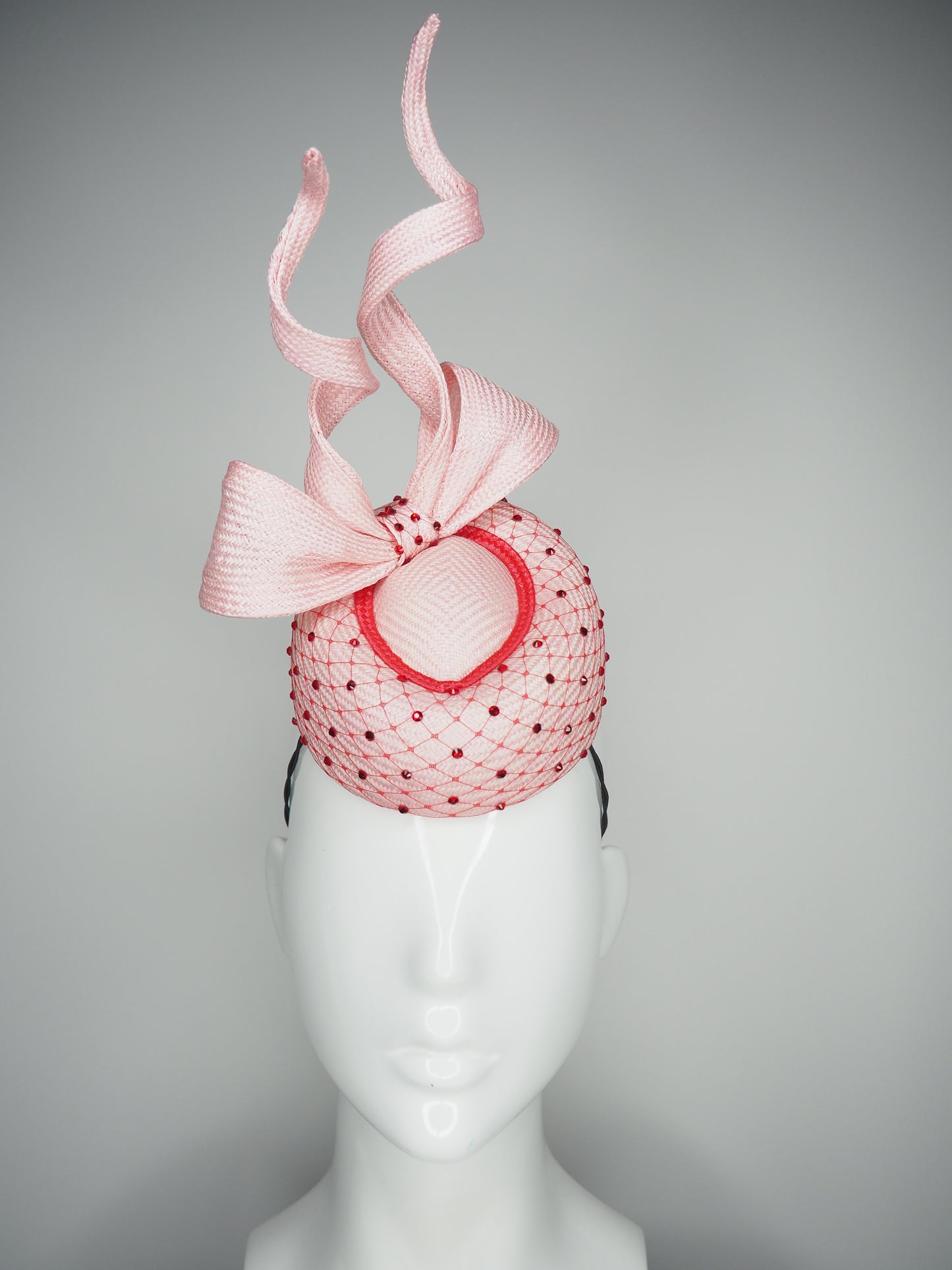 Cupids Bow - Baby pink Pork pie Pillbox with red veil and crystal detail and sculpted bow.