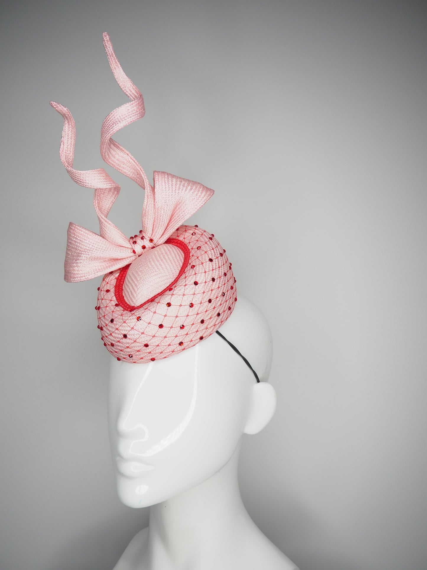 Cupids Bow - Baby pink Pork pie Pillbox with red veil and crystal detail and sculpted bow.