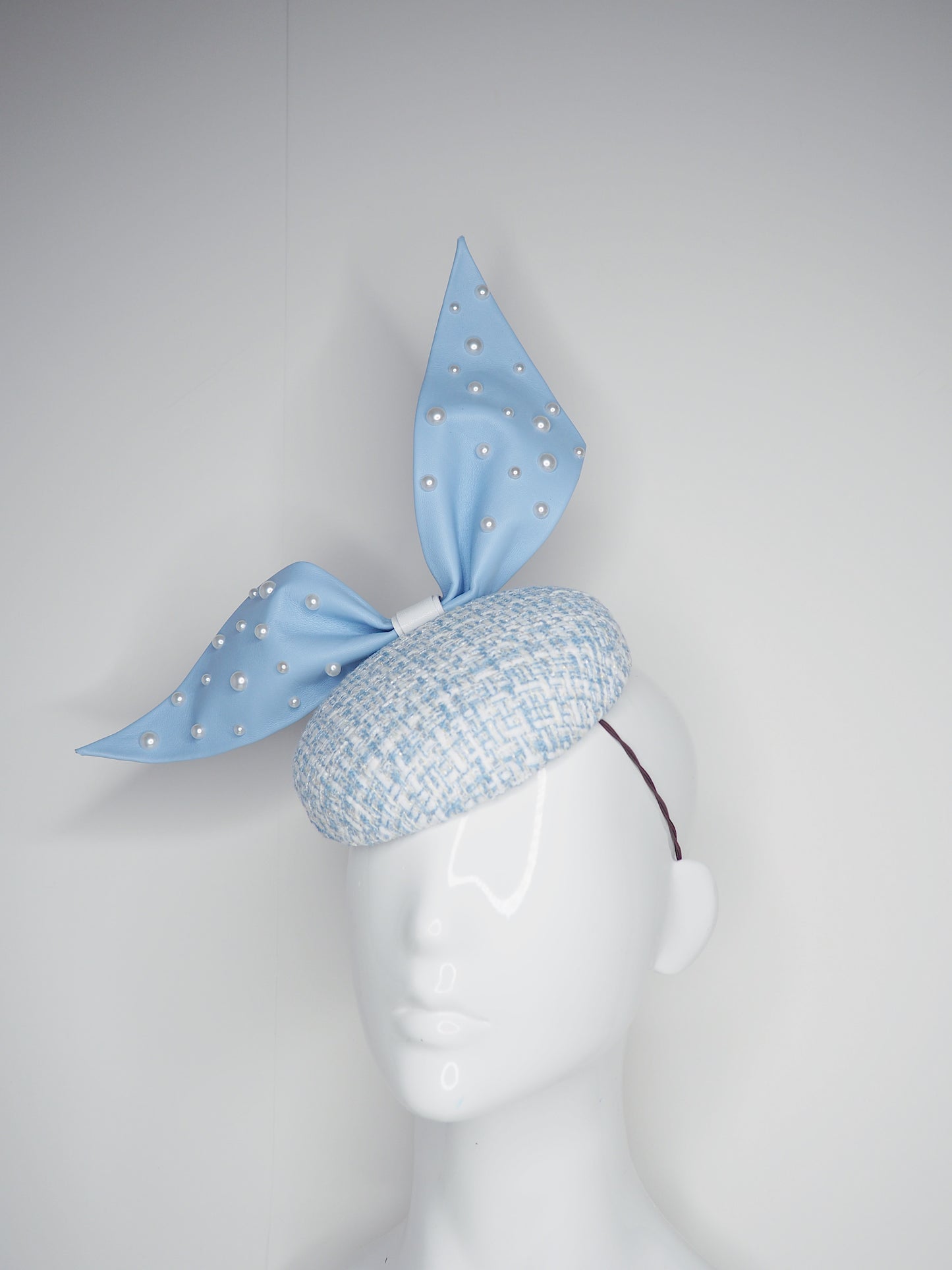 Blue pearl - Blue wired leather bow with pearl feature on a white and blue tweed button base with lurex flecks
