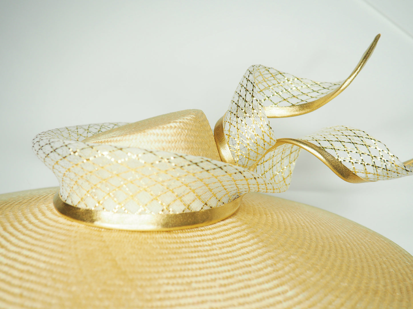 Gilded horizon  - Natural Straw broad brimmed slanted crown parissisal with white and gold lurex leather edged swirl crinoline detail.