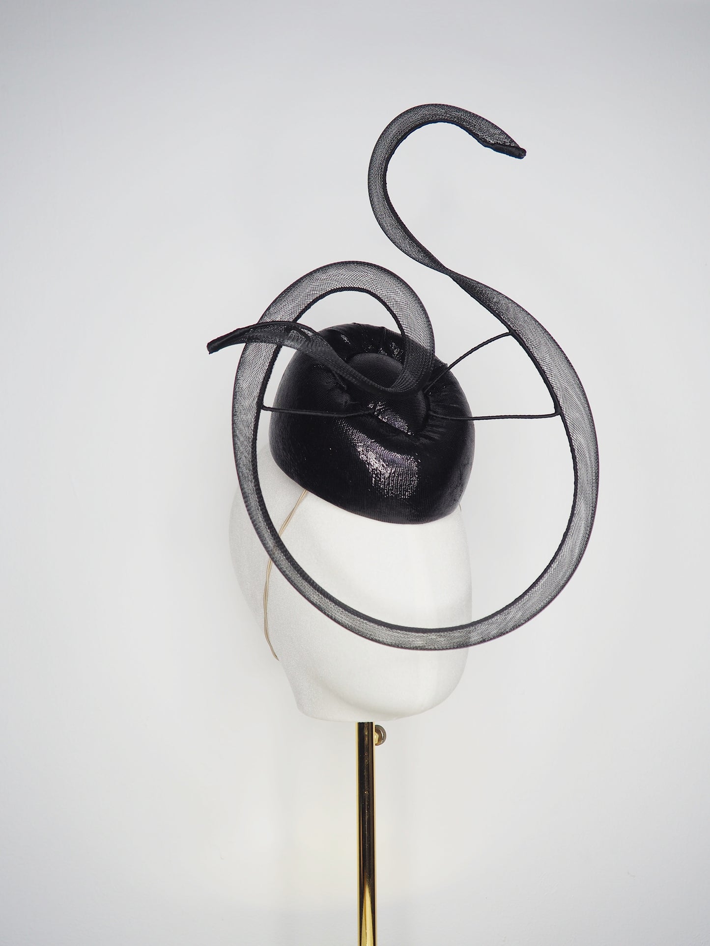 Black Swan - A sleek black lurex pillbox inspired by the graceful silhouette of a swan gliding across water.