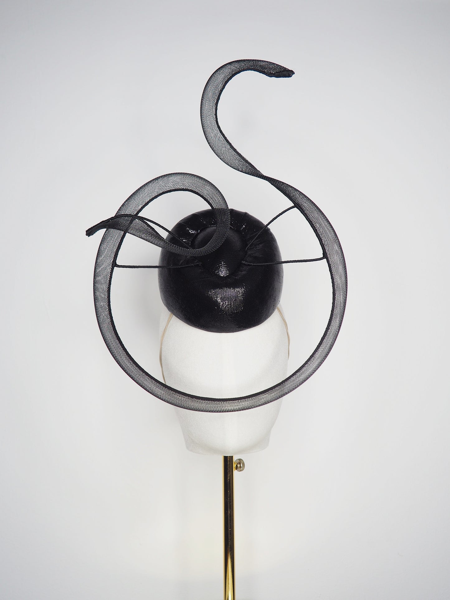 Black Swan - A sleek black lurex pillbox inspired by the graceful silhouette of a swan gliding across water.