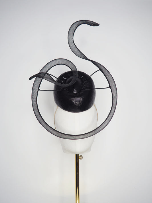Black Swan - A sleek black lurex pillbox inspired by the graceful silhouette of a swan gliding across water.