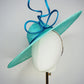 Sea Glass - A dramatic pale aqua asymmetrical brim featuring a sculptural turquoise bow, crystal detailing and delicate veiling.
