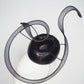 Black Swan - A sleek black lurex pillbox inspired by the graceful silhouette of a swan gliding across water.