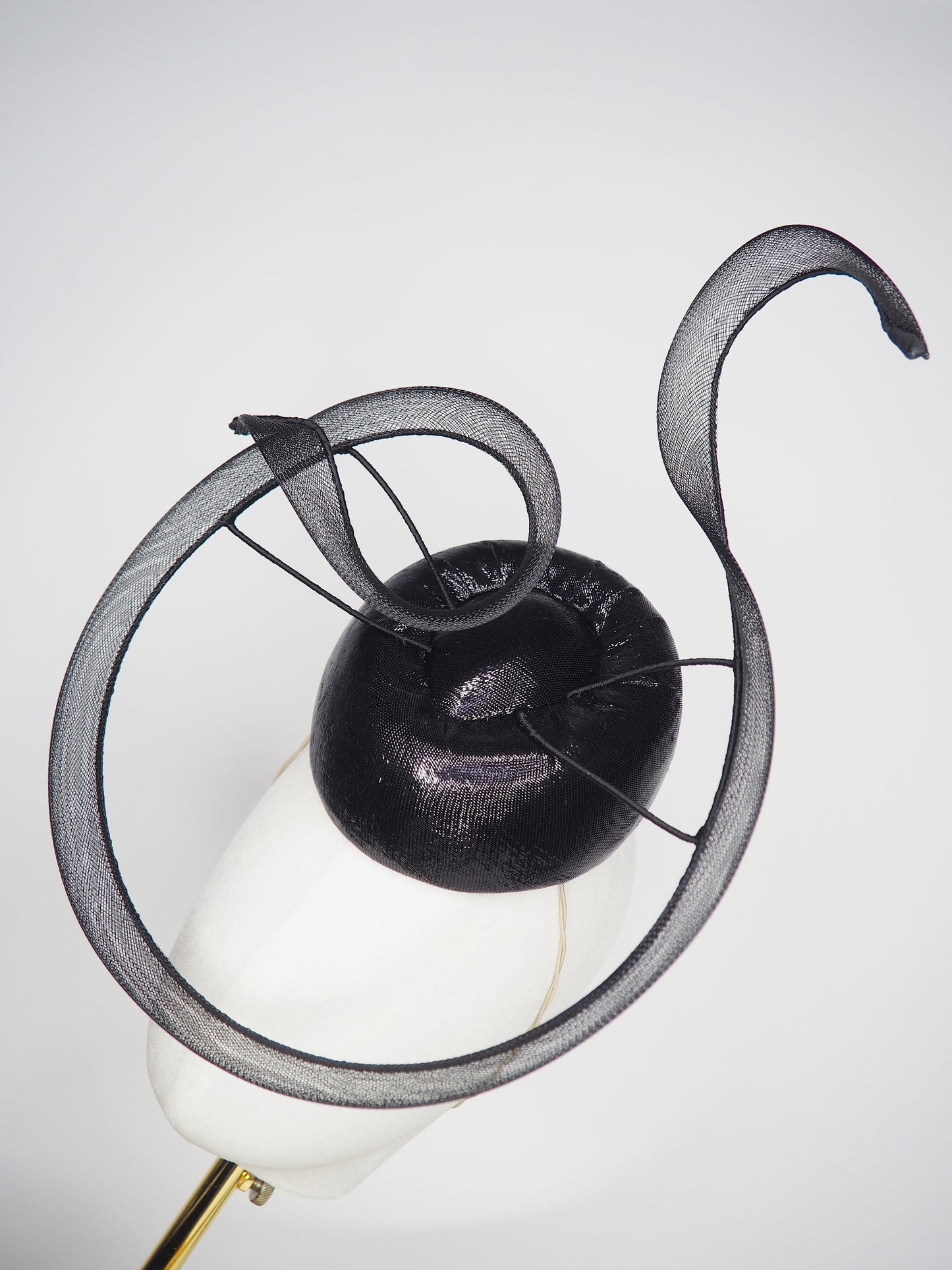 Black Swan - A sleek black lurex pillbox inspired by the graceful silhouette of a swan gliding across water.