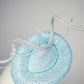 Blue Lagoon - A sophisticated pale aqua pillbox layered with shimmering lurex mesh and sculptural metallic swirls.