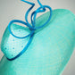 Sea Glass - A dramatic pale aqua asymmetrical brim featuring a sculptural turquoise bow, crystal detailing and delicate veiling.