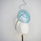 Blue Lagoon - A sophisticated pale aqua pillbox layered with shimmering lurex mesh and sculptural metallic swirls.