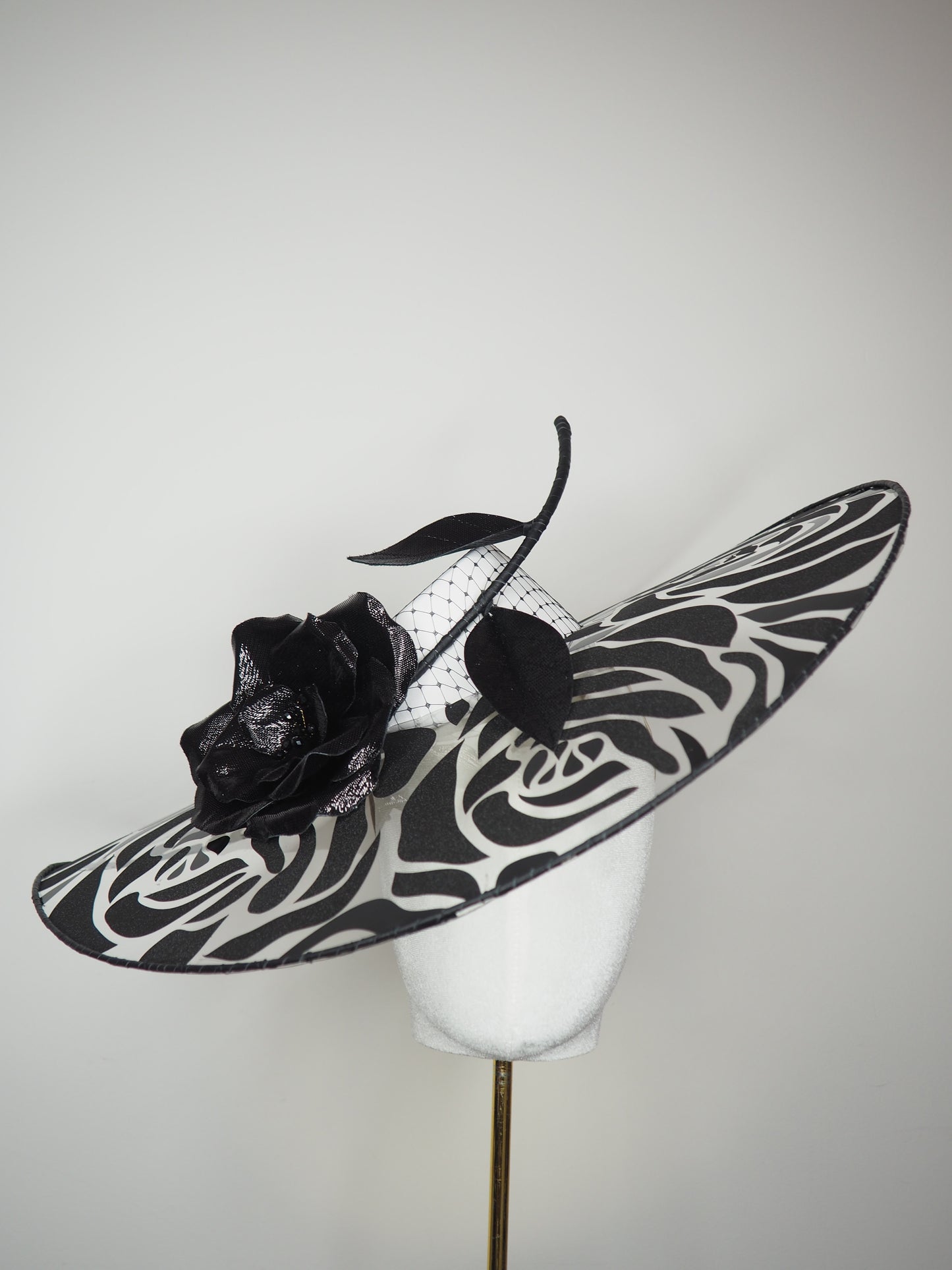 De Ville Rose - Sweeping crystoform wired brim with black rose petal pattern and single shiny dramatic rose with white leather veiled crown