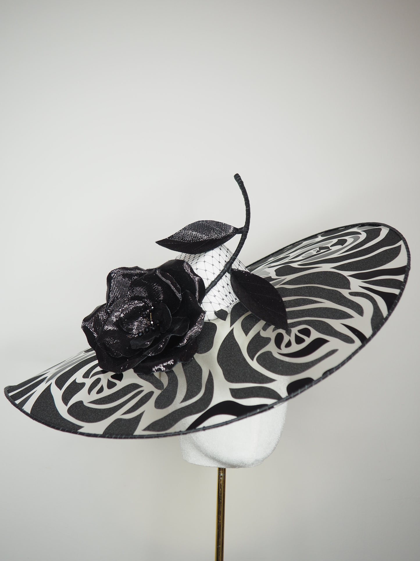 De Ville Rose - Sweeping crystoform wired brim with black rose petal pattern and single shiny dramatic rose with white leather veiled crown