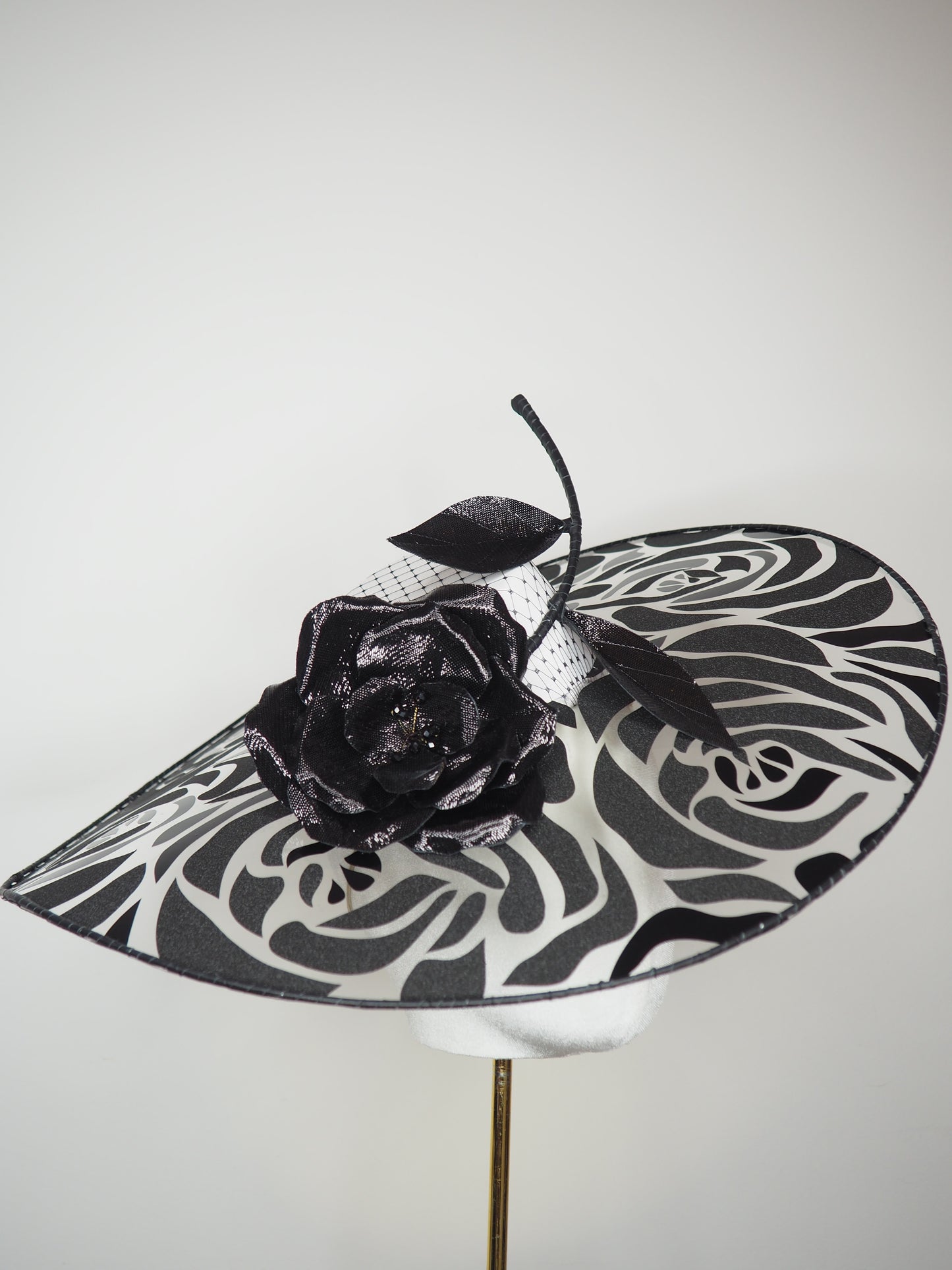 De Ville Rose - Sweeping crystoform wired brim with black rose petal pattern and single shiny dramatic rose with white leather veiled crown