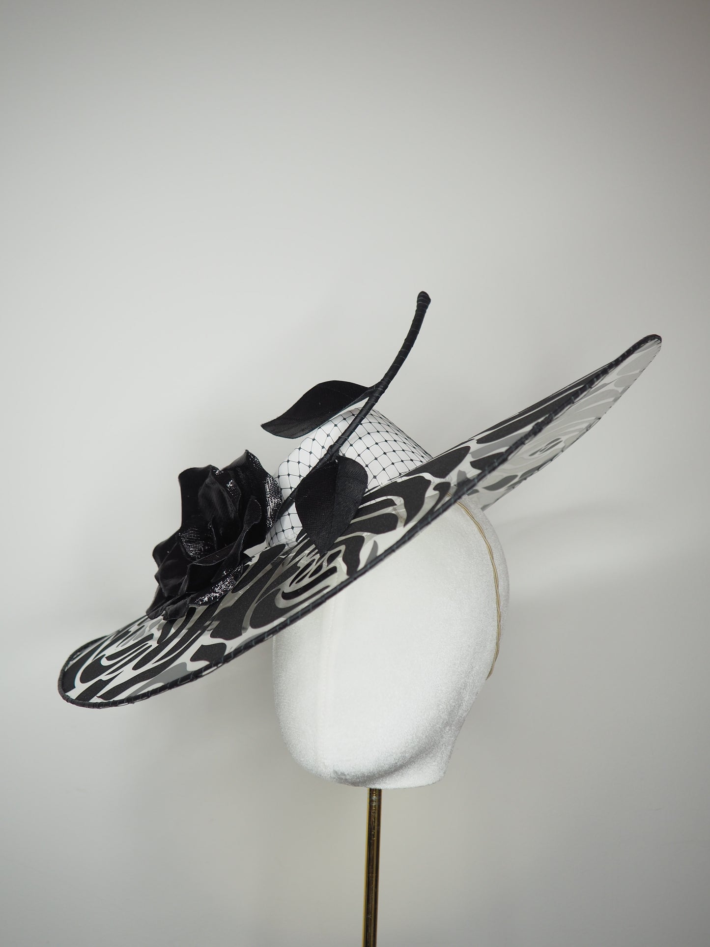 De Ville Rose - Sweeping crystoform wired brim with black rose petal pattern and single shiny dramatic rose with white leather veiled crown