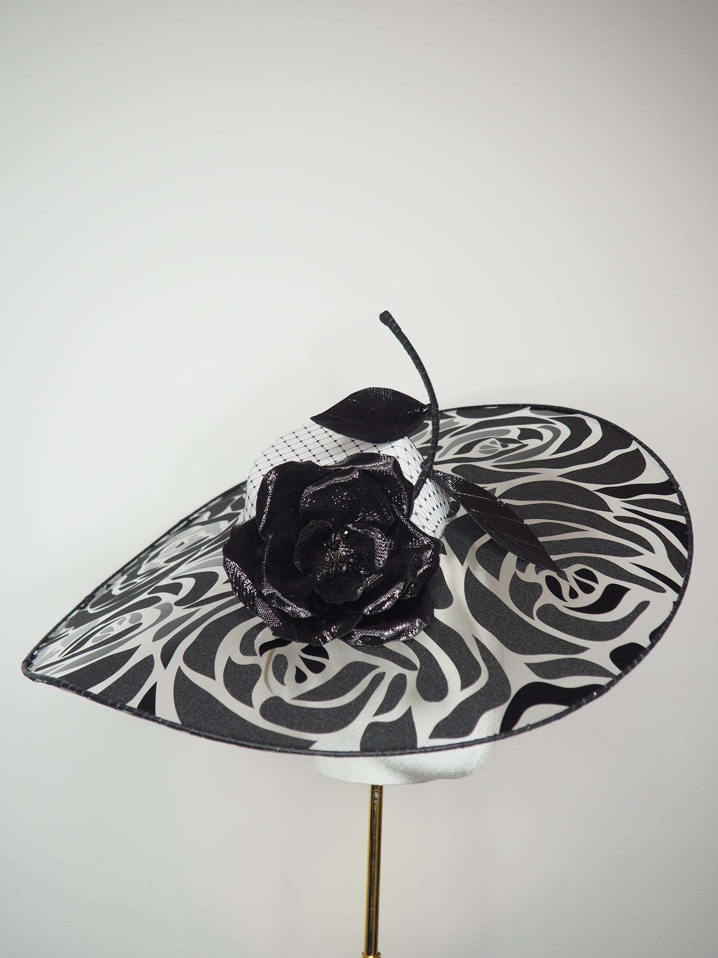De Ville Rose - Sweeping crystoform wired brim with black rose petal pattern and single shiny dramatic rose with white leather veiled crown