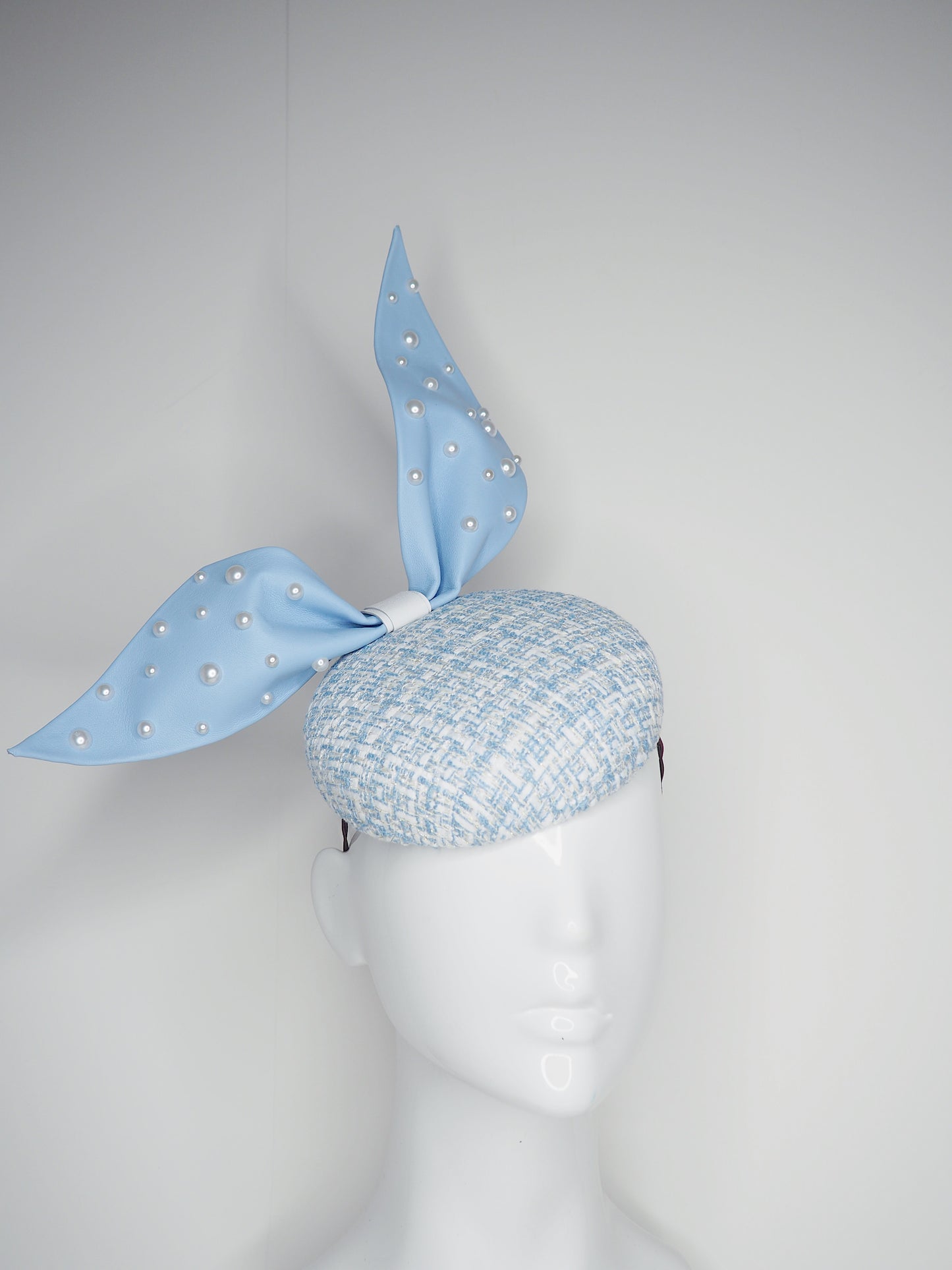 Blue pearl - Blue wired leather bow with pearl feature on a white and blue tweed button base with lurex flecks