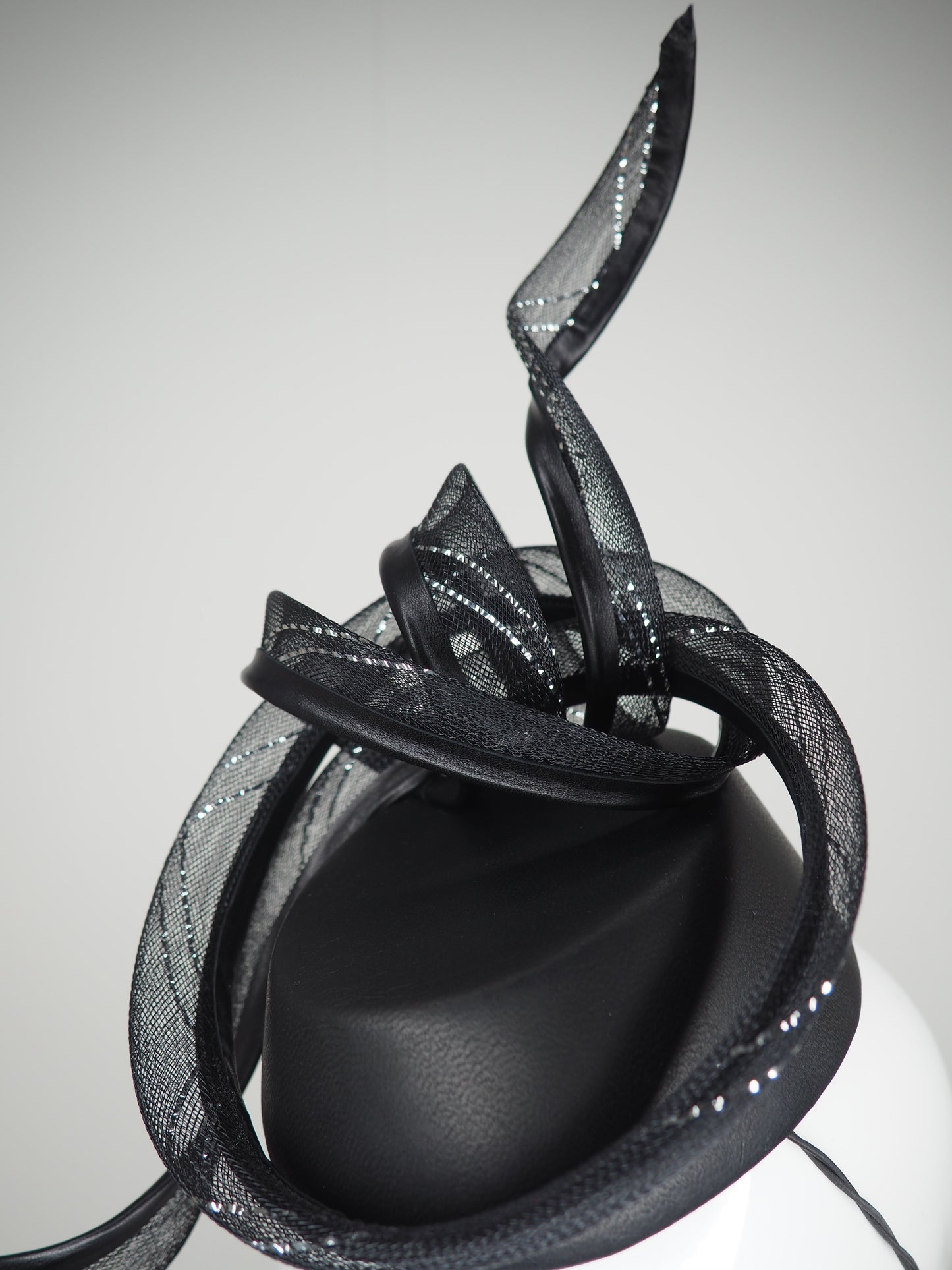 Serpentia - Black asymetrical leather sharp pillbox with crinoline swirl knot