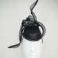 Serpentia - Black asymetrical leather sharp pillbox with crinoline swirl knot