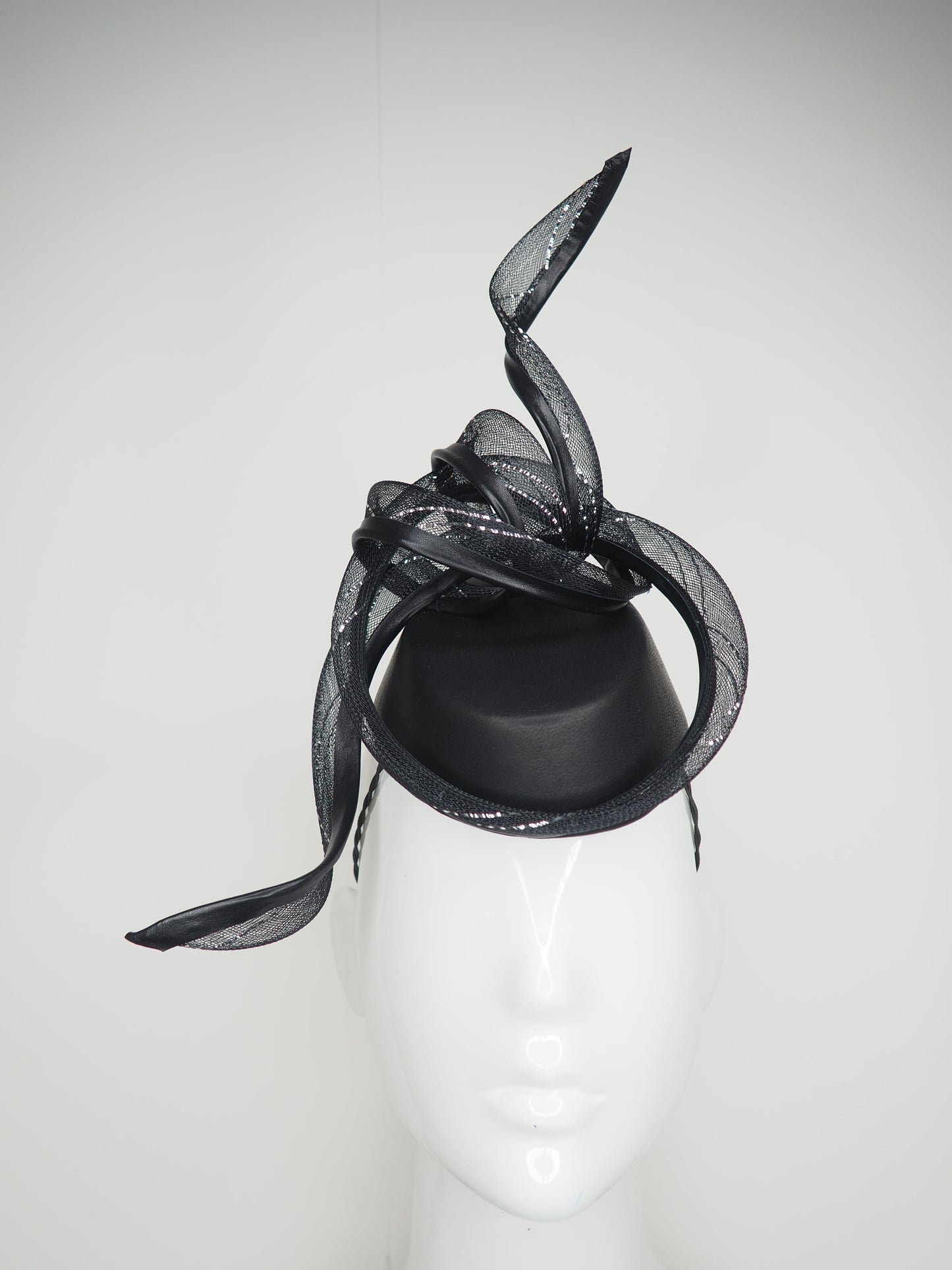 Serpentia - Black asymetrical leather sharp pillbox with crinoline swirl knot