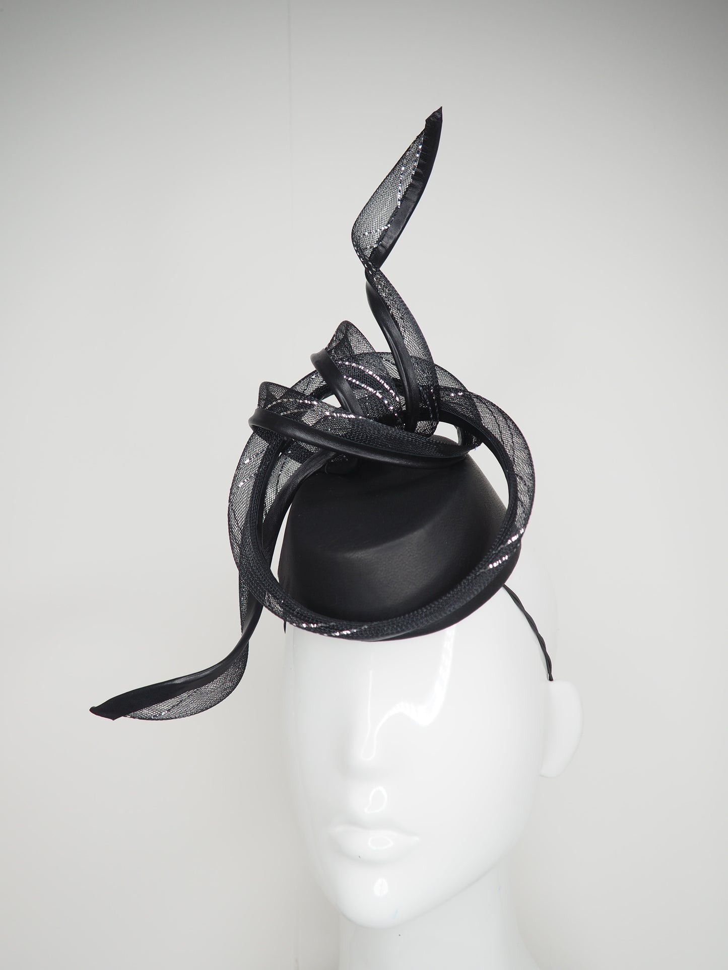 Serpentia - Black asymetrical leather sharp pillbox with crinoline swirl knot