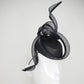 Serpentia - Black asymetrical leather sharp pillbox with crinoline swirl knot