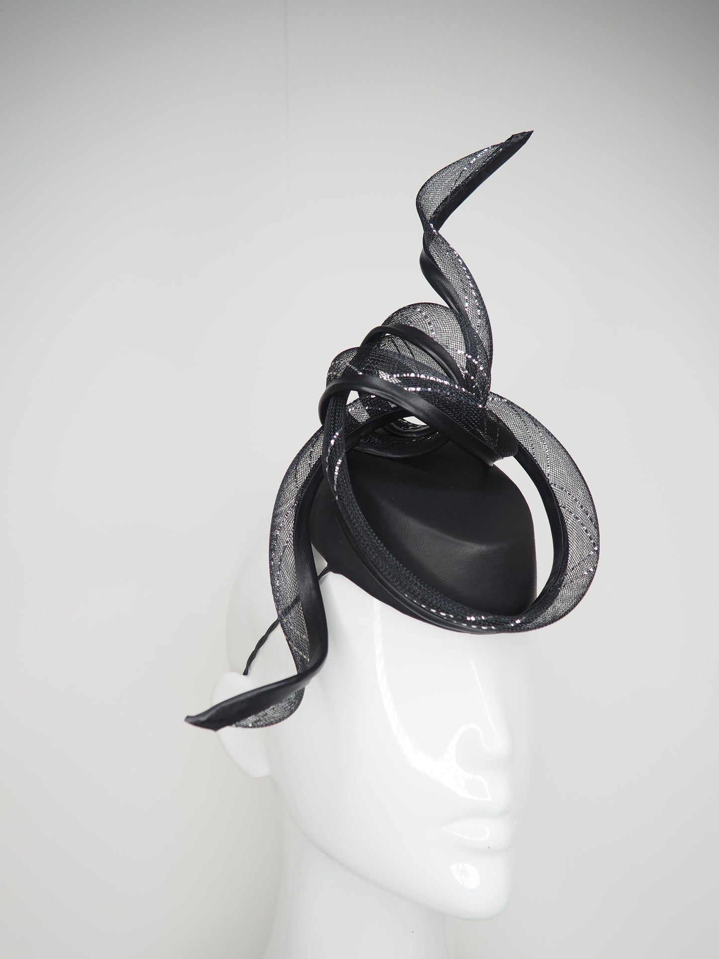 Serpentia - Black asymetrical leather sharp pillbox with crinoline swirl knot